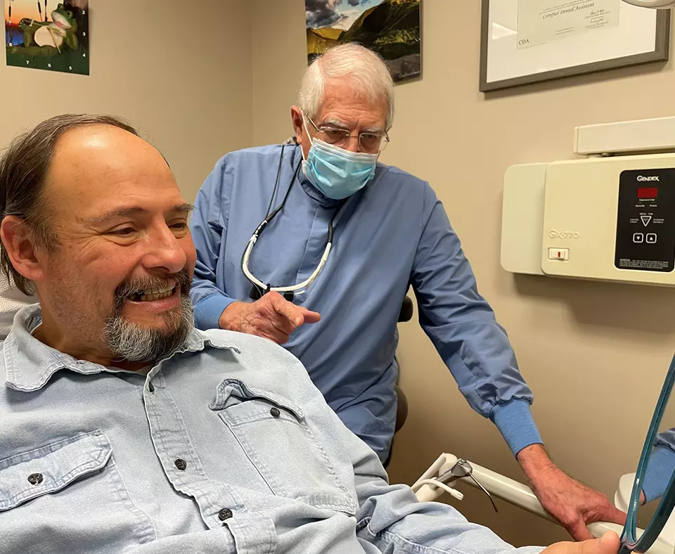Northeast Delta Dental photo showing a dentist and a patient looking in a mirror at the dental work..