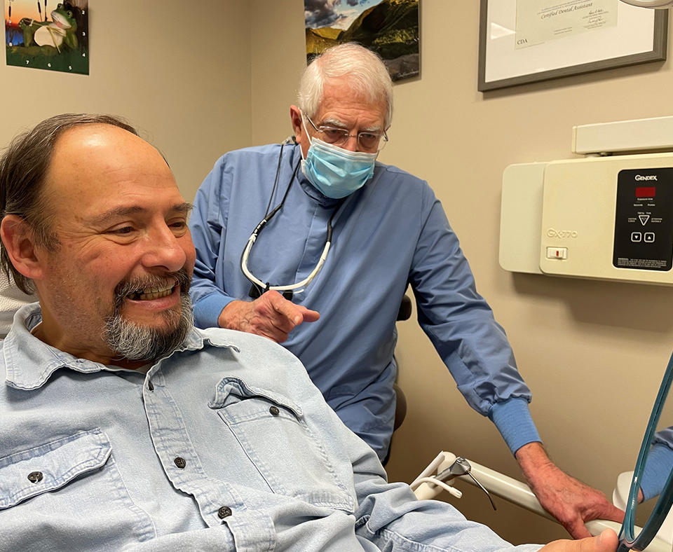 Northeast Delta Dental photo showing a dentist and a patient looking in a mirror at the dental work..