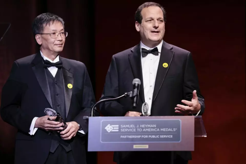 NIST researchers Long Phan and Marc Levitan stand at a podium after accepting their Service to America medals.