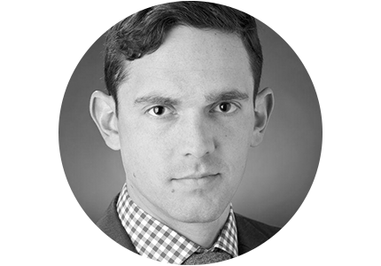 black and white headshot of Russell Maier, a person with short curly hair, wearing a suit