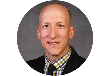 a smiling person with a bald head, wearing a suit and tie