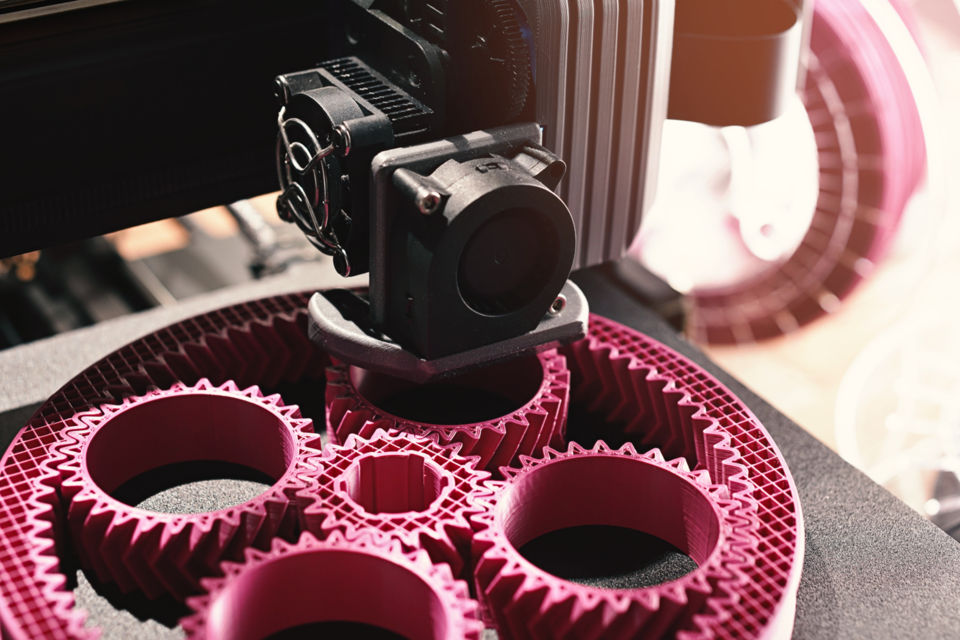 a 3-D printer prints hot pink gears for additive manufacturing