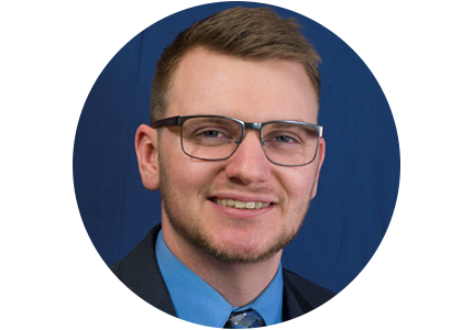 William Feeney, a person with short brown hair, a beard, and glasses, smiles for a professional headshot.