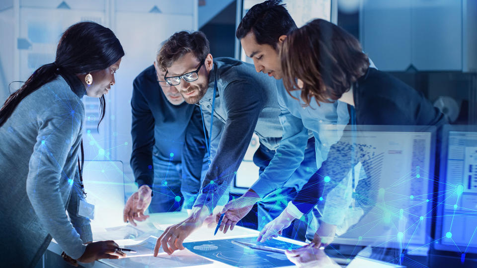 A group of colleagues plan out designs on a desk