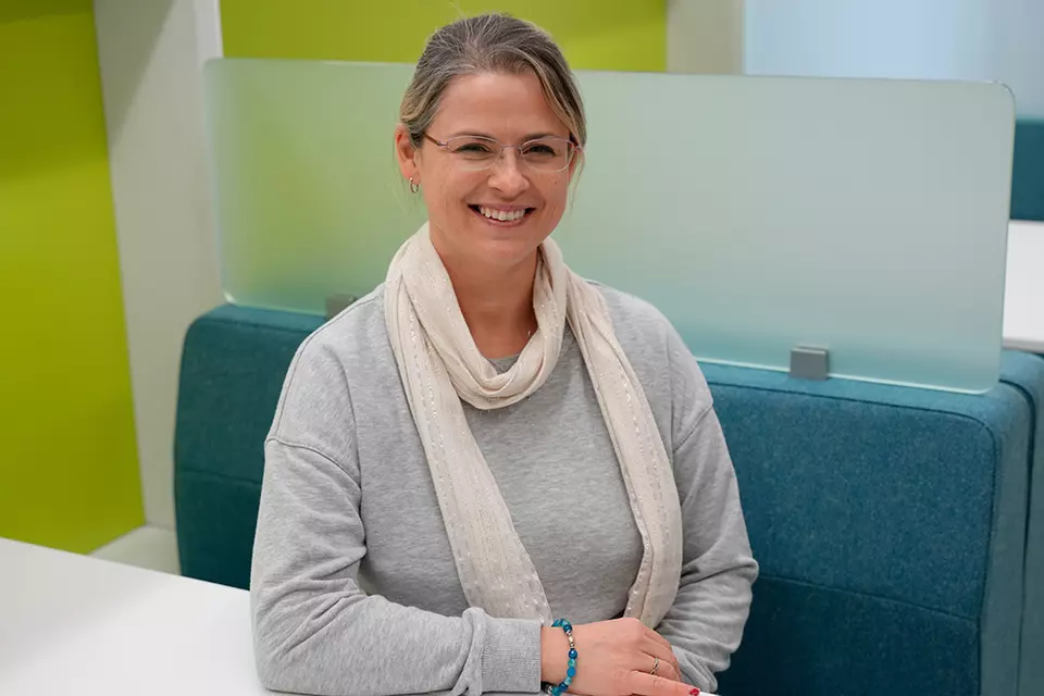 Justyna Zwolak poses smiling, seated at a colorful workspace in the NIST library. 