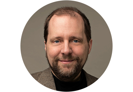 Headshot of Edward Tate, a man with short brown hair and beard, smiling