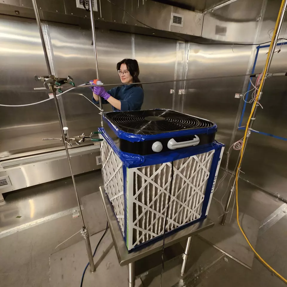 NIST researcher setting up air cleaner experiments in large stainless steel environmental chamber