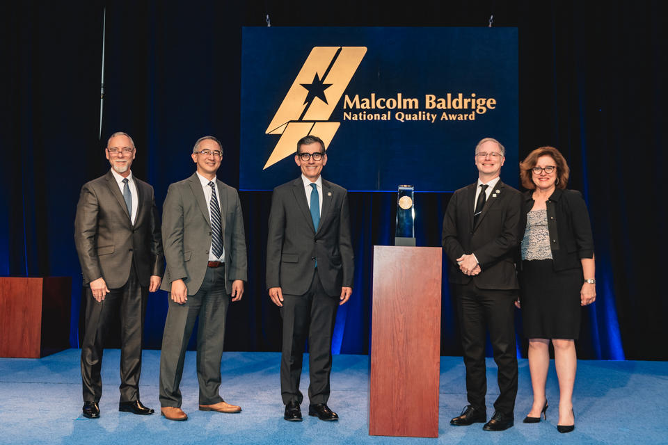 Alamo Colleges District standing beside their 2024 Baldrige Award Crystal.