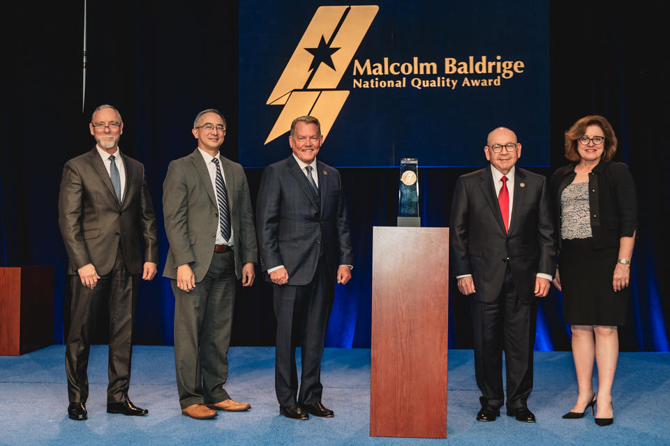 Chickasaw Nation Department of Health standing beside their 2024 Baldrige Award Crystal.