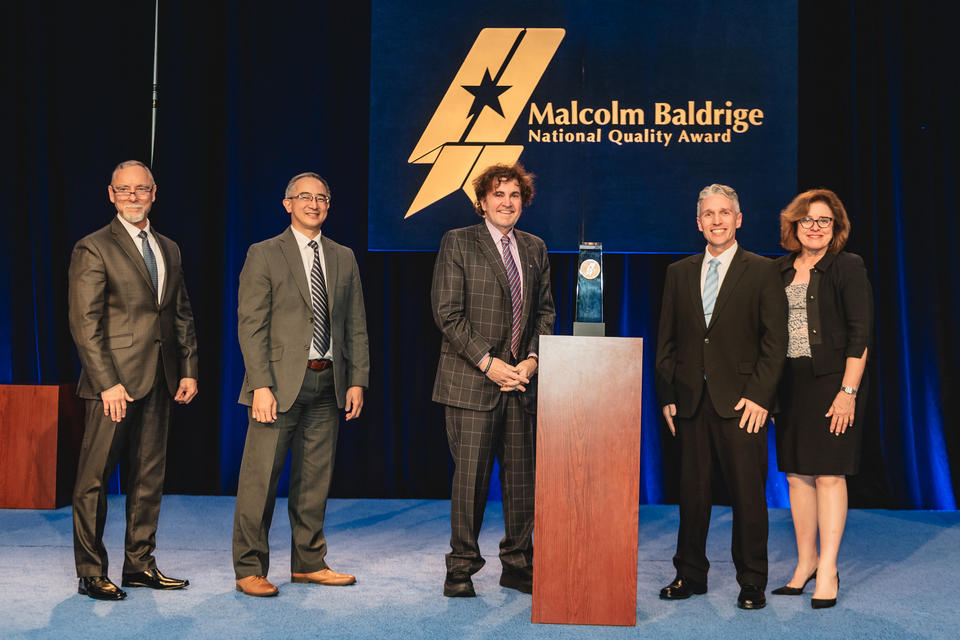 Northeast Delta Dental standing beside their 2024 Baldrige Award Crystal.