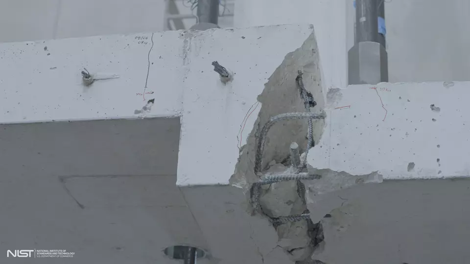 Close-up view of large crack in white concrete slab, with rebar showing.