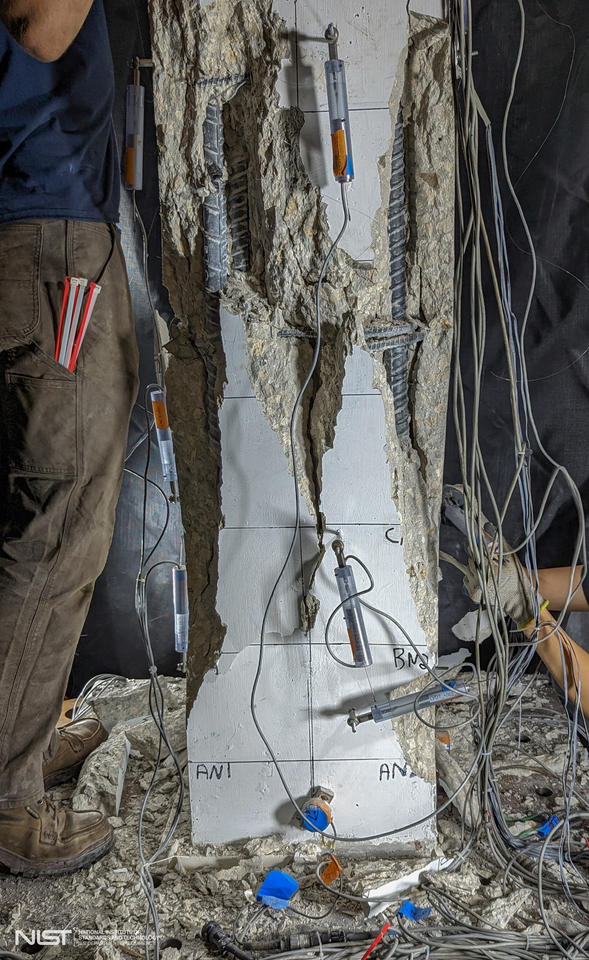 A vertical column with sensors attached has shredded-looking cracks and broken parts. 