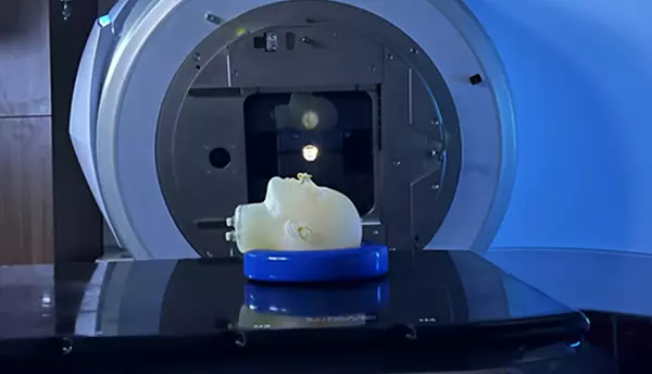 A model of a human head lies face up on the platform of an MRI machine. 