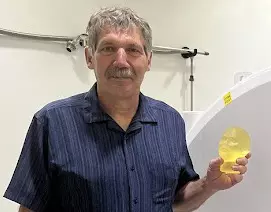 Stephen Russek poses in the lab holding a small model of a human head.