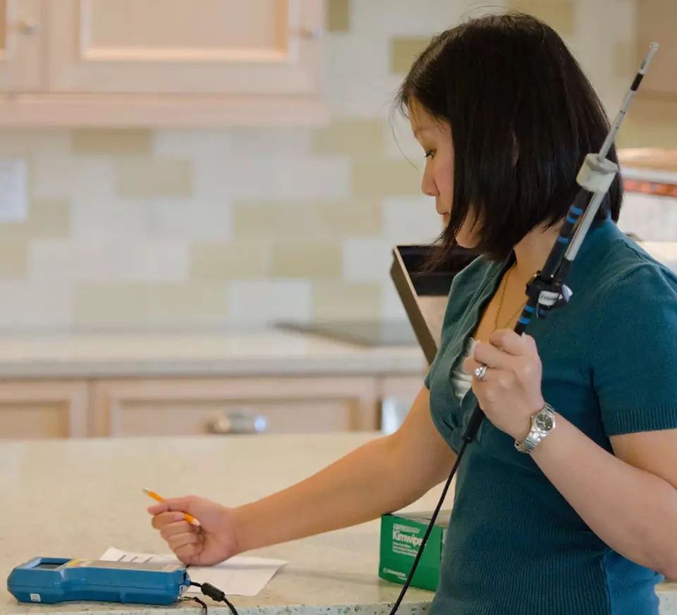 Lisa Ng holds an air testing device in the kitchen of a NIST research house.