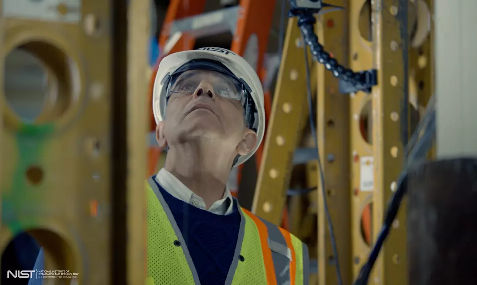 Photo of structural elements surrounding man with helmet and glasses looking up 