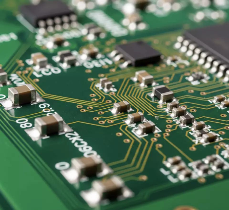 Close-up of an emerald green circuit board highlighting the three-dimensional topography of this miniature electronic ecosystem.