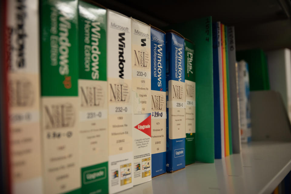 Boxes of Microsoft Windows software with NSRL stickers are lined up on a metal shelf.
