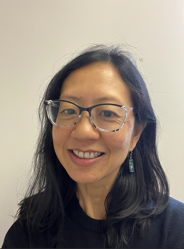 A woman with long black hair and glasses, smiling for a photo. 