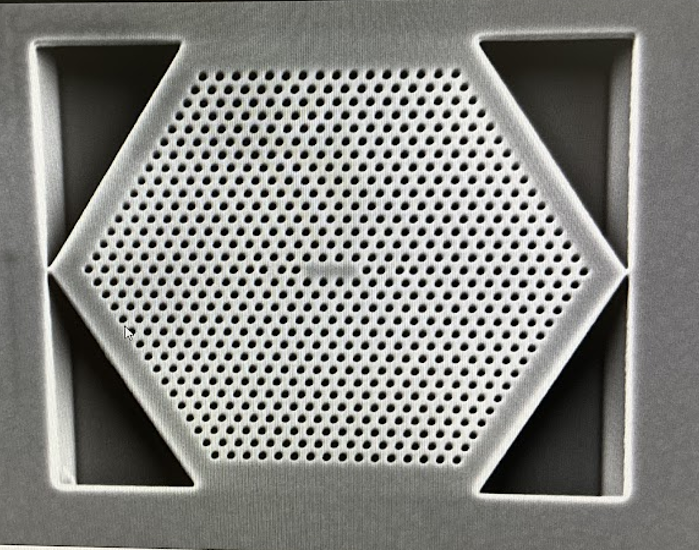Close-up view of a hexagon shape with rows of tiny holes filling it. 