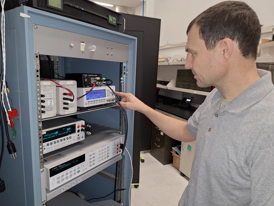 Matt Spidell stands looking into a server cabinet that holds several electronic devices wired together.