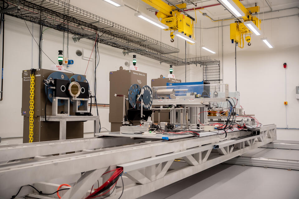 Complex scientific devices and wiring sit on a platform in front of three large X-ray machines. 