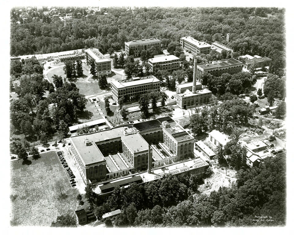 Historical aerial view of the National Bureau of Standards campus surrounded by trees.