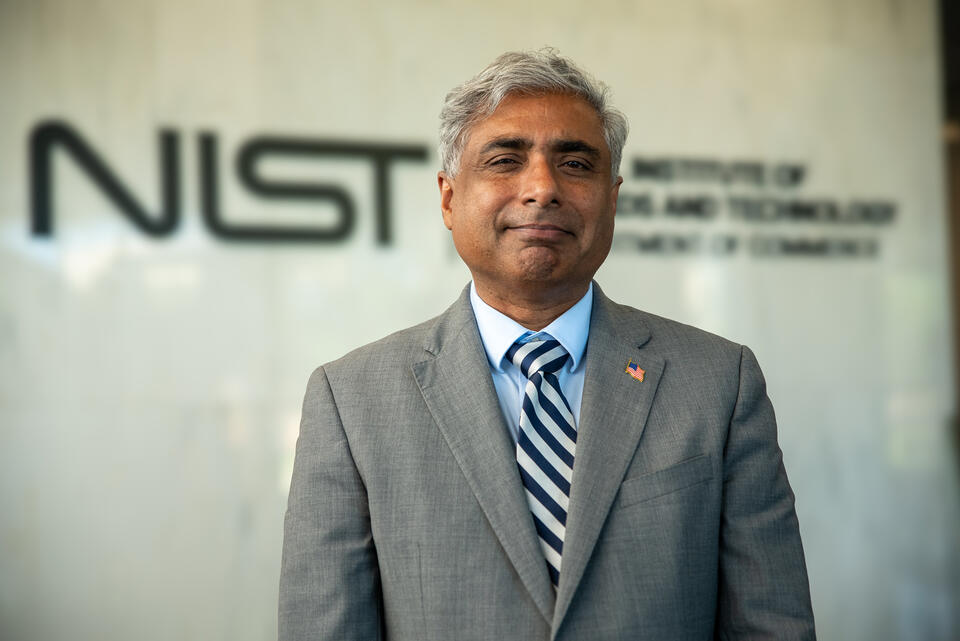 NIST director standing in front of the NIST logo
