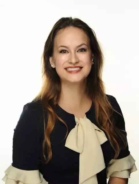 Smiling woman in a navy blue and white dress.