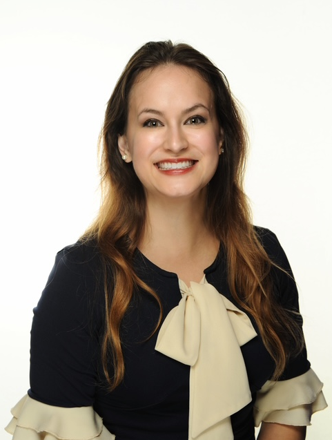 Smiling woman in a navy blue and white dress.