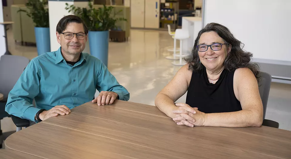 Jay Hendricks and Barbara Goldstein sit smiling at a table in the NIST library. 