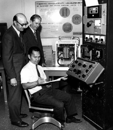 Three men sit at a dashboard