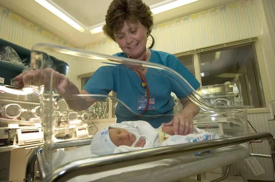 Female nurse looking at a baby in a NICU