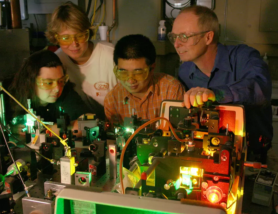 Four individuals looking at a piece of lab equipment