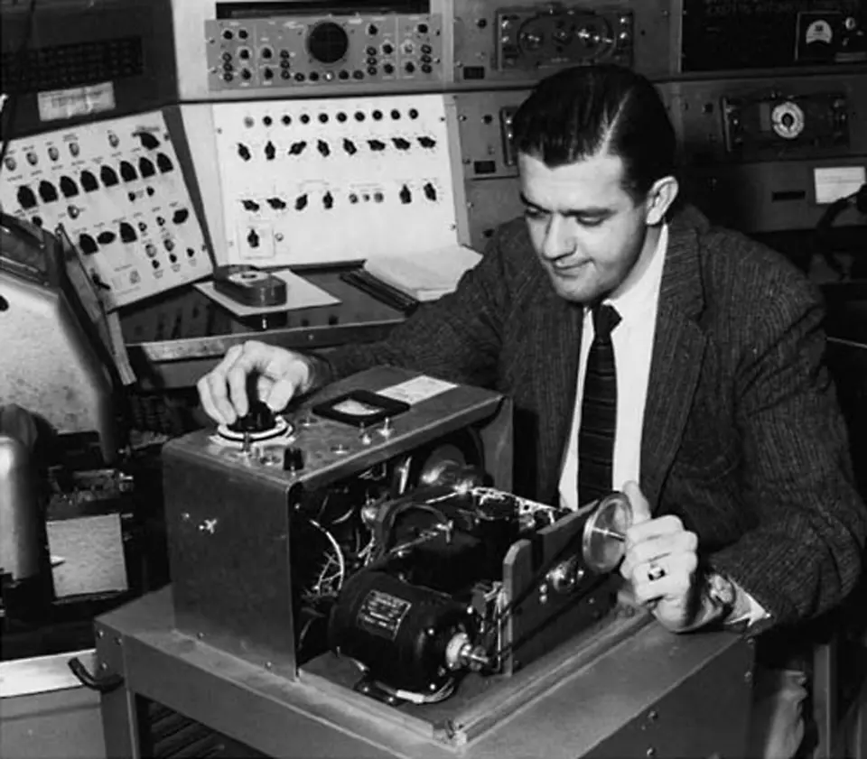 b&w image. Man sitting at one of the first computers.