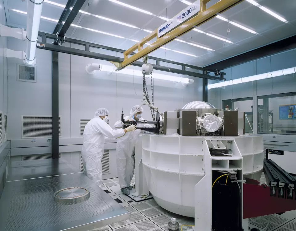 Two men in bunny suits with lab equipment