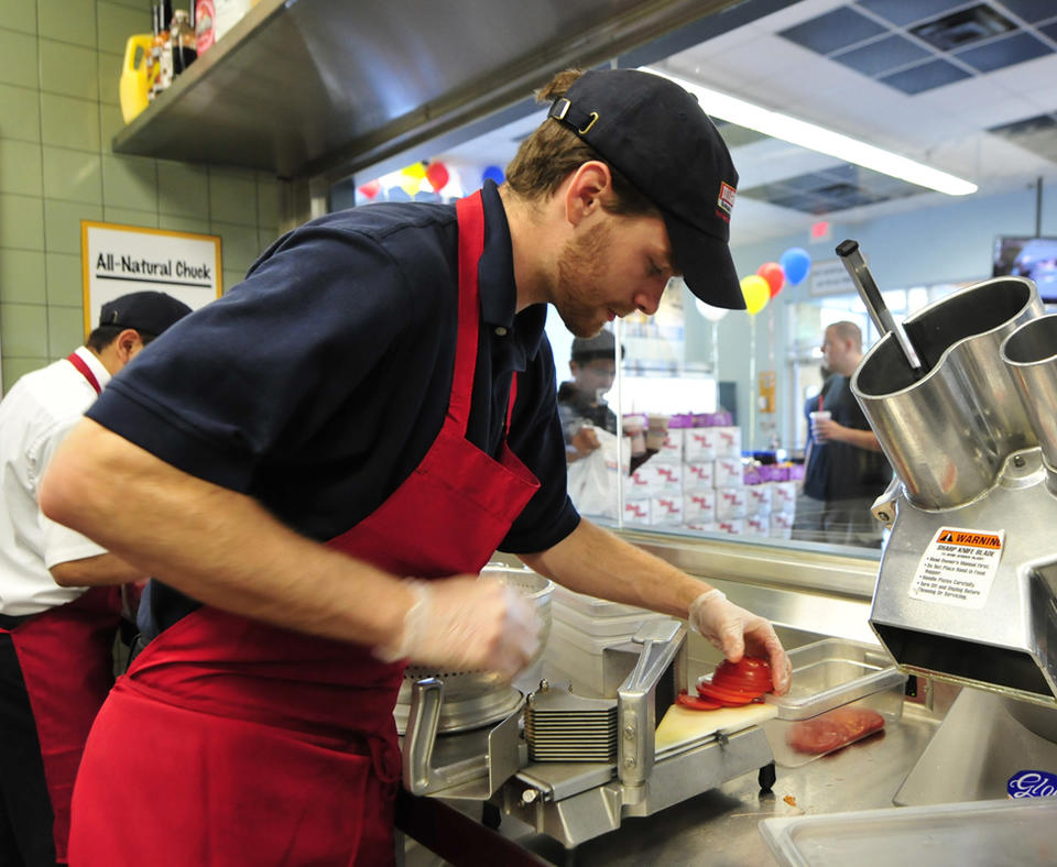 K&N Management photo of employee slicing tomatoes.