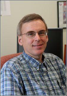 Edward (Ed) Garboczi, a person with short brown hair and glasses, smiles for the camera.