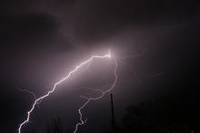 Photo of purplish black sky with a streak of bright lightning