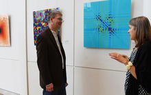 Woman and man talking beside wall with several square illustrations of science art