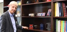 Blonde-haired man standing by bookcase