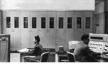 Lady on left and man on right at desks facing lab equipment