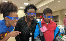 Two women and a young boy look on with interest at something out of frame 