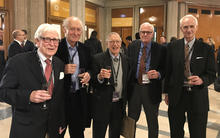 group of five men holding champagne flutes