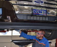 worker at Don Chalmers Ford is shown servicing vehicle