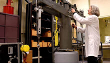 Blonde woman in white lab coat working on equipment