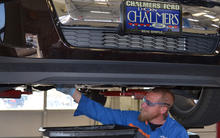 Don Chalmers Ford employee under vehicle changing the oil of a car.