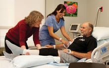 Hill Country Memorial Strategies blog photo of two female nurses helping a male patient in hospital bed lift his leg.