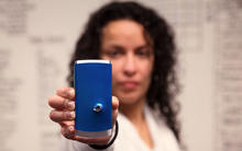 Woman holding a cell phone with a bullet hole in it out at arm's length. 