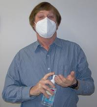 Bill MacCrehan masked and administering hand sanitizer to himself